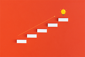 A minimalist graphic shows a series of white rectangular steps ascending diagonally on an orange background