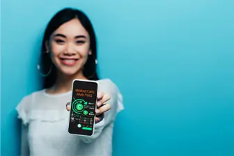 A woman displays a smartphone with a green screen, showcasing a blank canvas for digital content or app development.