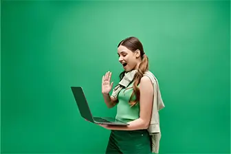 A woman seated at a table, working on a laptop with a camera positioned nearby.